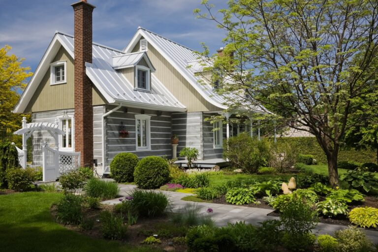 Stacked log home with Amur Maackia tree in front yard at springtime, Quebec, Canada