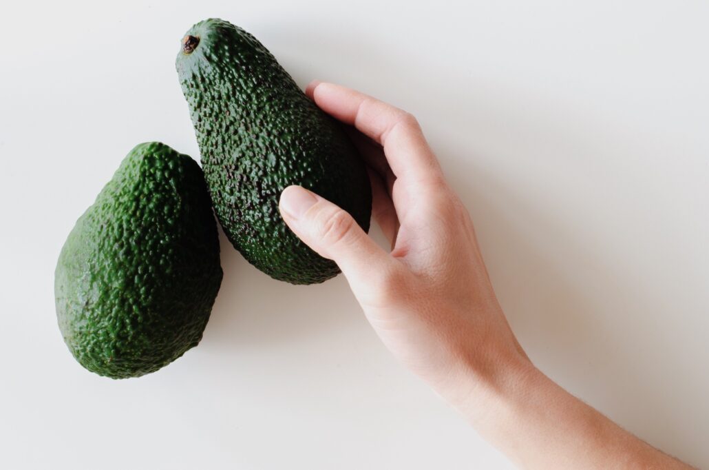 Woman's hand takes avacado from the table.